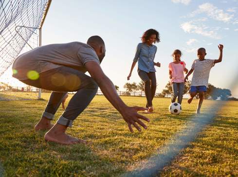 Image taken through football goal net of family playing football