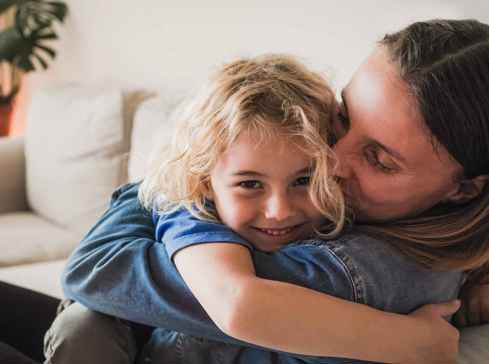 Mother and child cuddling - child smiling at camera