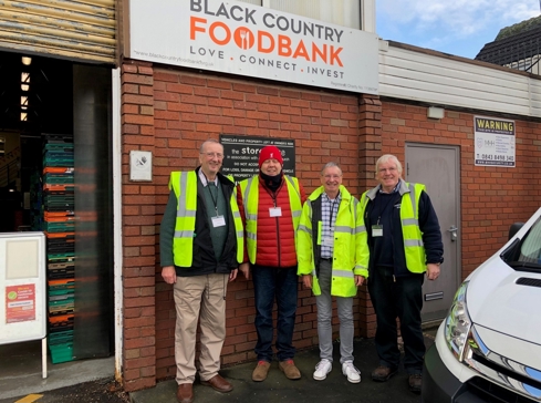 Four men wear high-vis standing outside a food bank