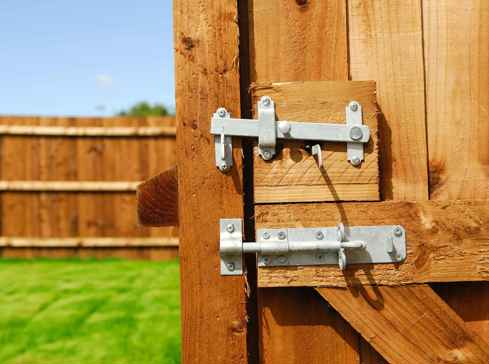 Close up of the latch of a garden gate with a wooden fence in the background