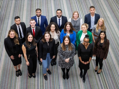 Group of trainee solicitors all looking up at the camera smiling